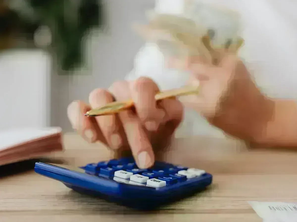 Persona calculando con billetes en la mano: revisa ingresos y ratio antes de simular la hipoteca